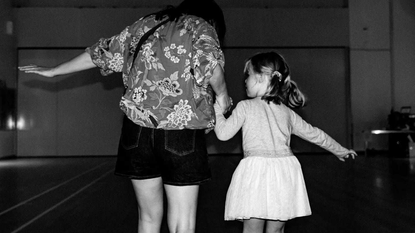 A black and white photo from behind of a mother and child roller skating