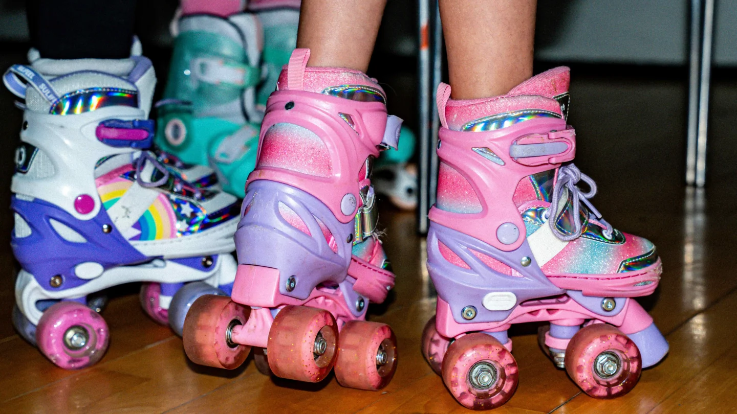 A close up of three children's feet in brightly coloured roller skates