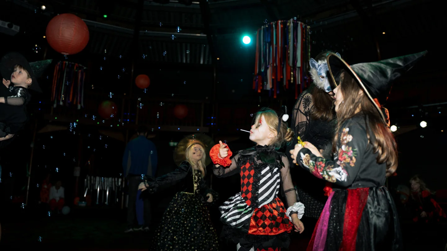 A photo of a dark dancefloor with children dressed up as witches and skeletons.
