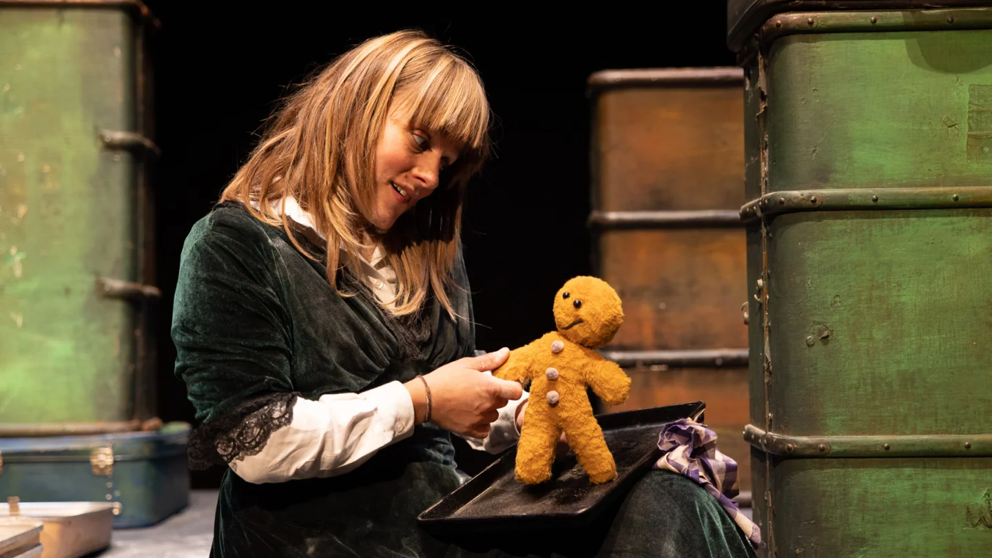 A person sitting down, holding a gingerbread man
