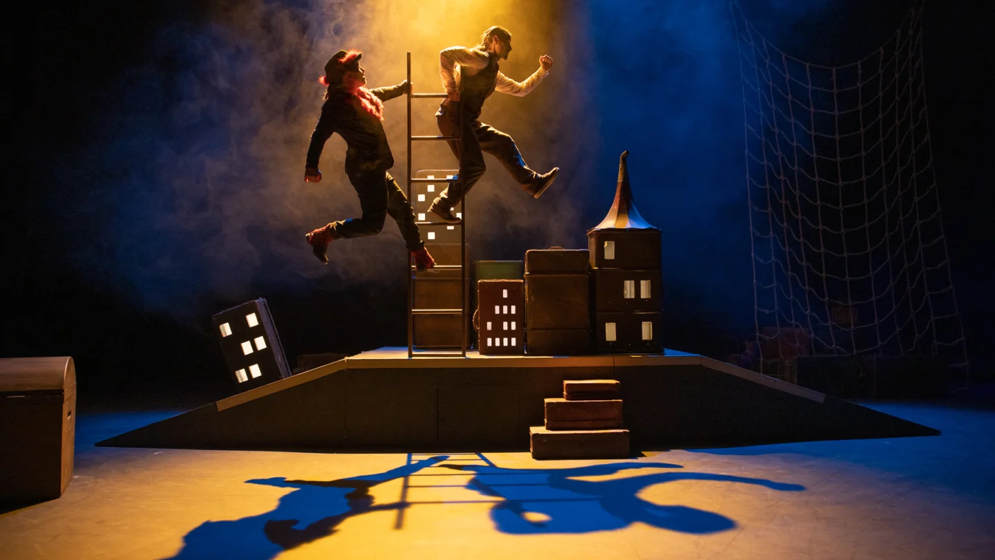 Two figures jumping in the air, silhouetted by light