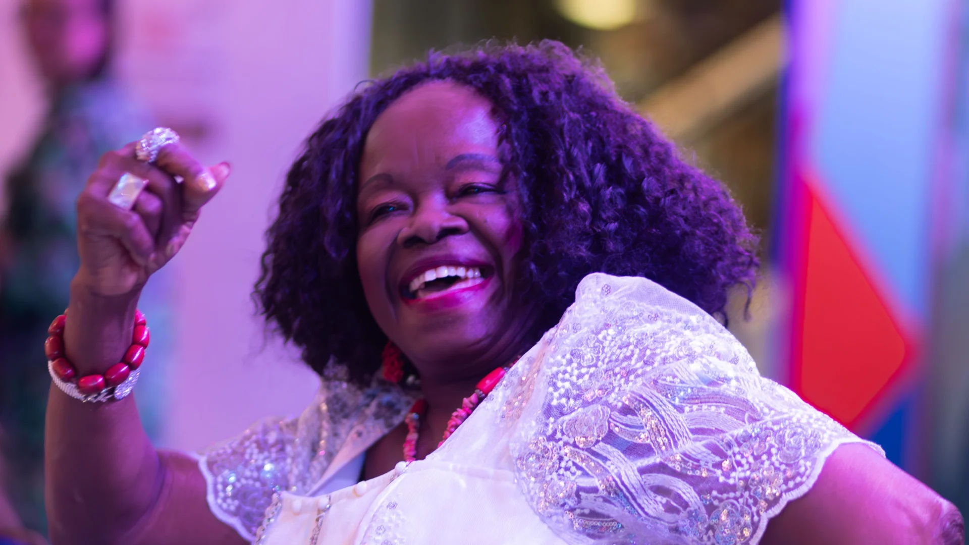 An older woman dancing with an enthusiastic smile on her face. The atmosphere is bright  and colourful and full of joy.