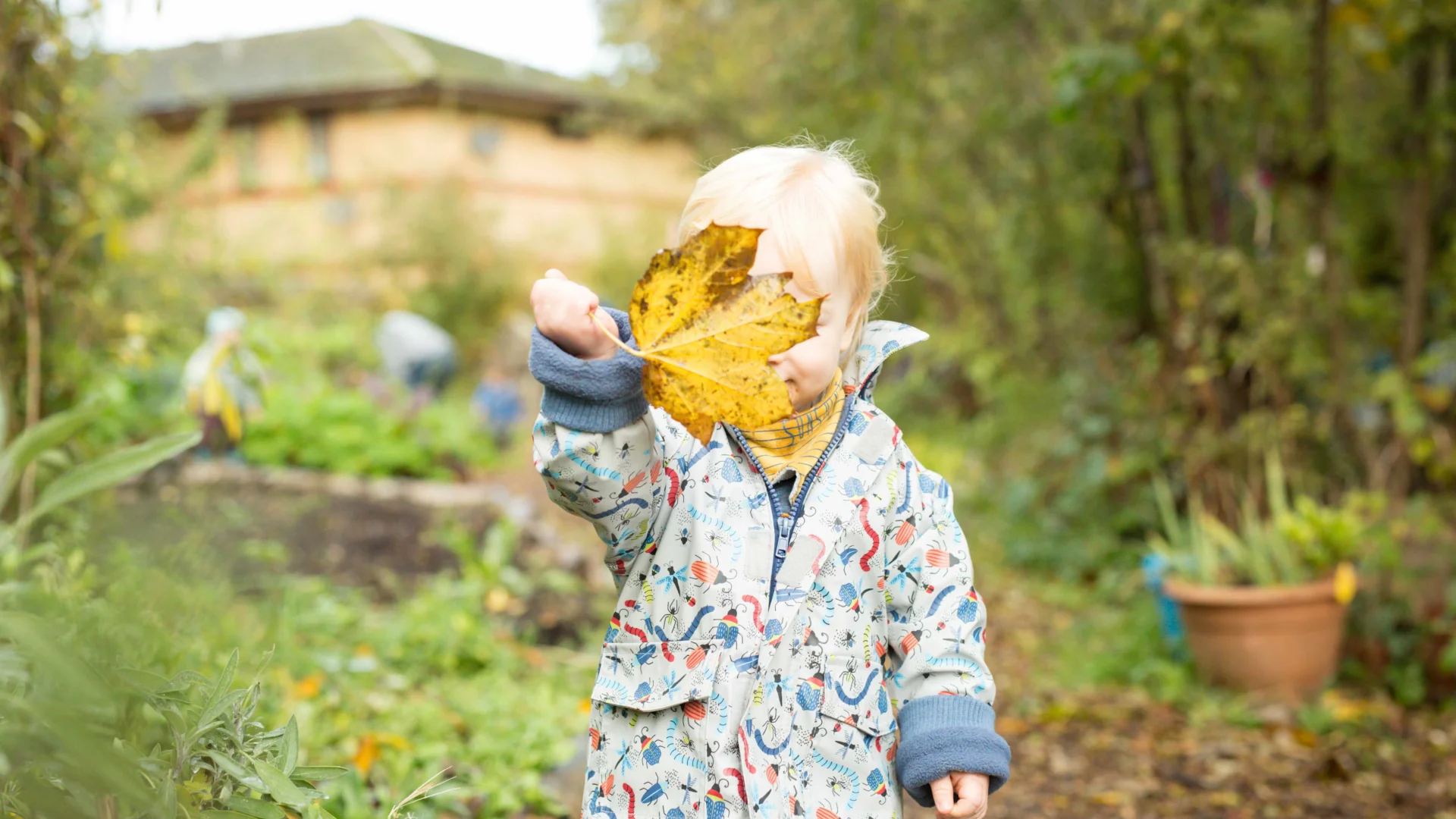 A child in a garden with a leaf in front of their face