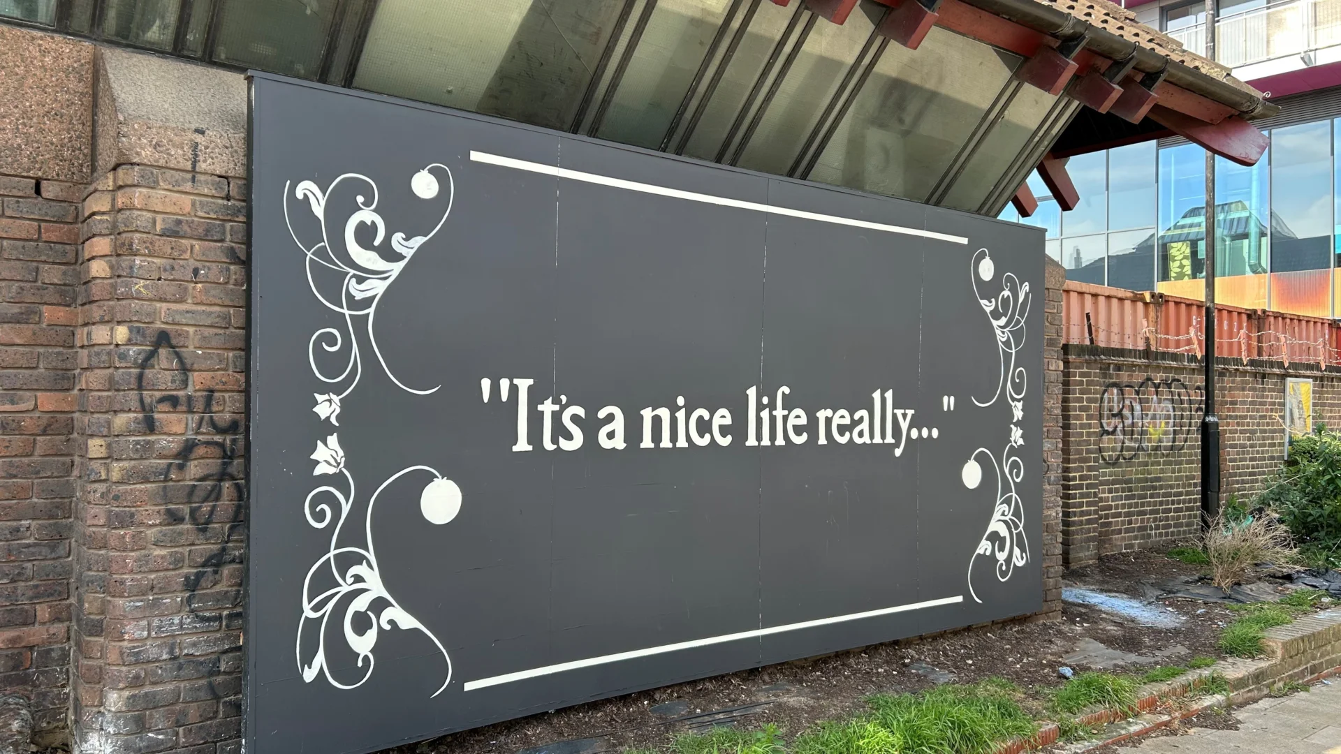 A black mural with white text reading 'It's a nice life really...'