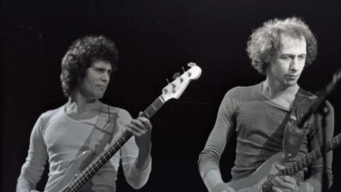 A black and white photograph of Dire Straits - two men with curly hair holding guitars - performing at the Albany in the 1970s.