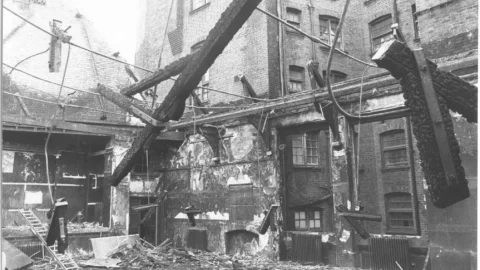 A black and white photograph of a room with the roof caved in and lots of rubble on the floor.