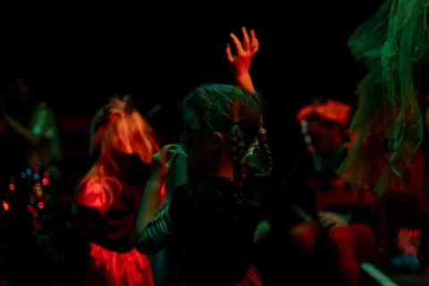 An arty, blurry photo of children dancing, bathed in green and orange light.