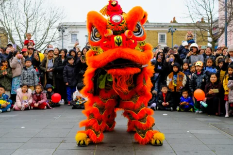 dragon suit looking at camera, surrounded by people