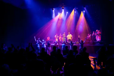Figures on a stage with blue and purple lighting