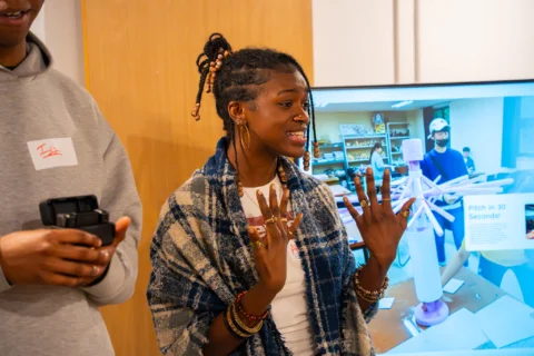 A person talking in front of a screen