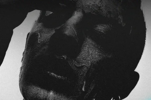 A black and white photograph of a person with their eyes closed.