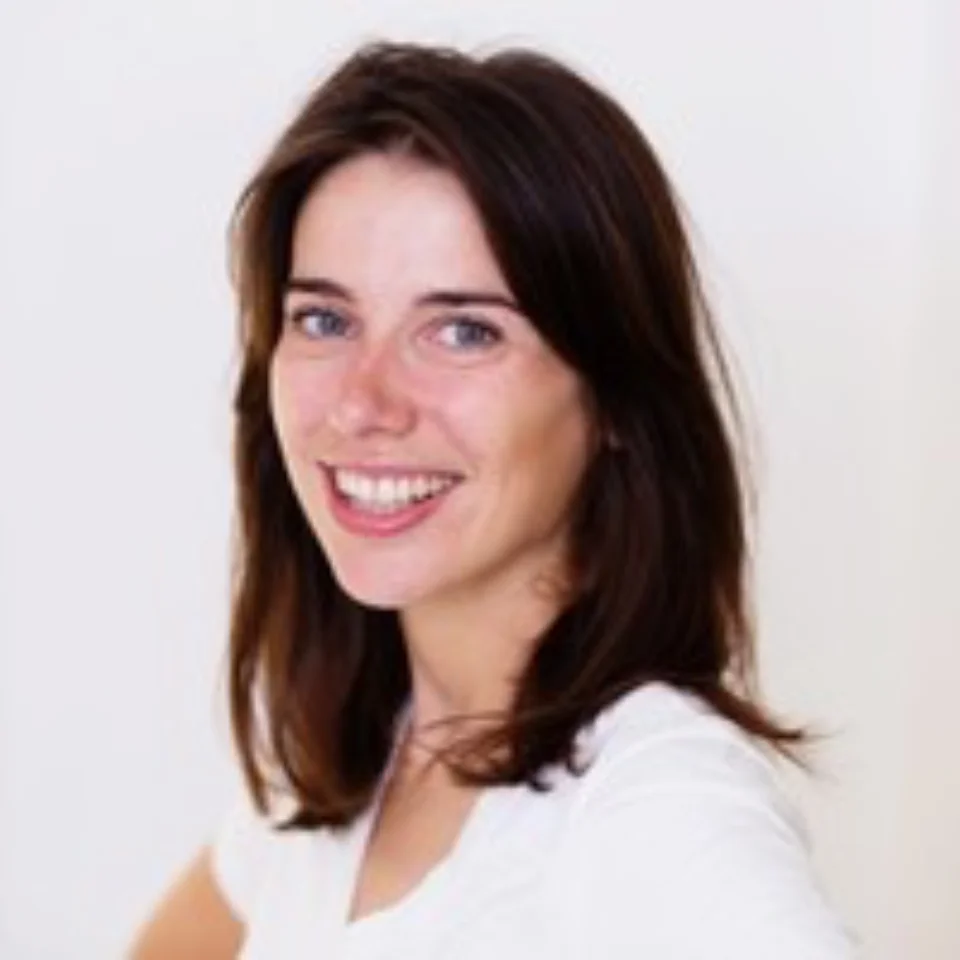 A headshot of Hayley Murphy, a white woman with dark brown hair, wearing a white t-shirt and stood in front of a white wall.